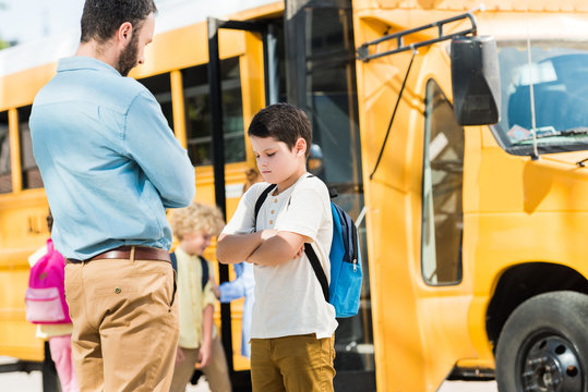 father preaching his son in front of school bus