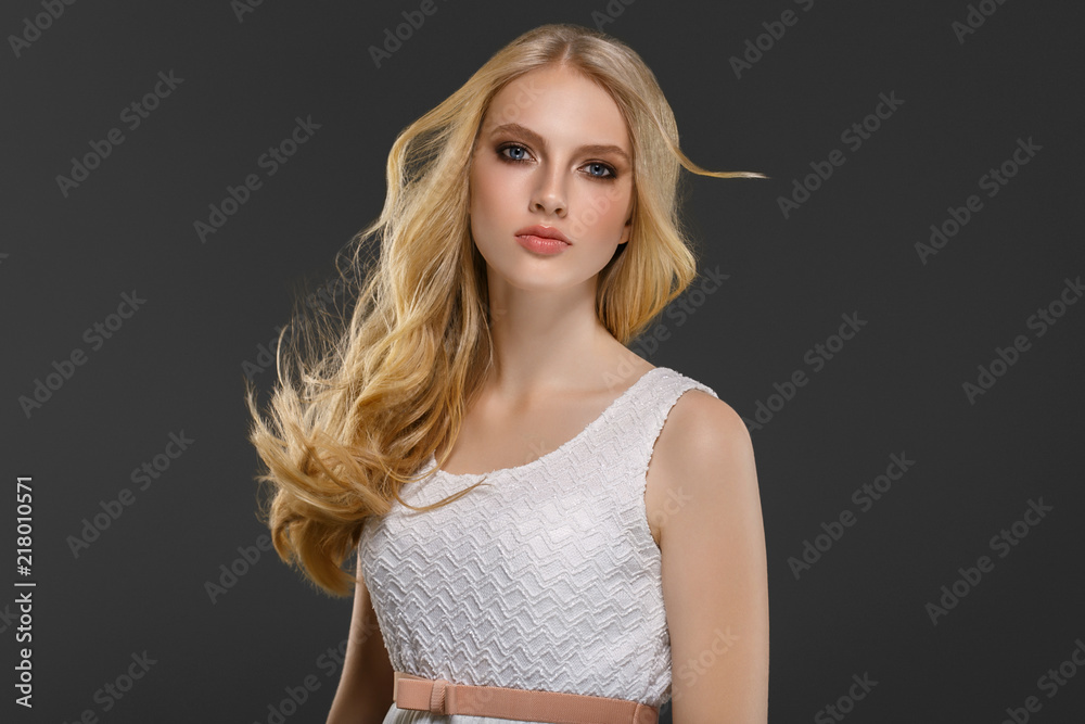 Wall mural Beautiful woman with long blonde hair over gray background beauty female