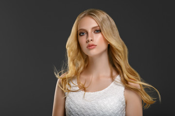 Beautiful woman with long blonde hair over gray background beauty female