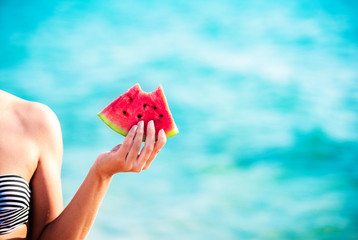 Fototapeta na wymiar Watermelon slice in woman hand over sea - POV. Summer beach concept. Tropical fruit diet.