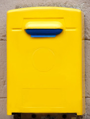 Yellow public mailbox on the wall on the wall of a building