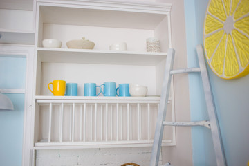 Fototapeta na wymiar Kitchen shelf with bright cups: yellow and blue.
