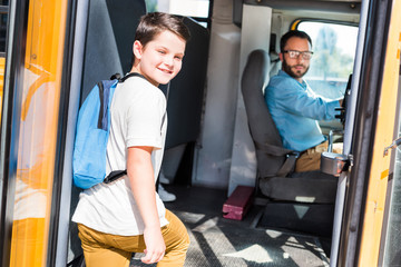 handsome school bus driver and schoolboy looking at camera