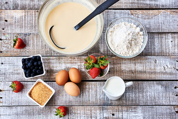 Flour in a bowl on  wooden background  eggs and milk, top view.
