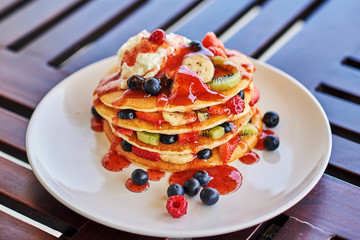 Pancake with ice cream and strawberry sauce on restaurant table