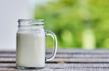 Glass of milk on table on blurred natural background
