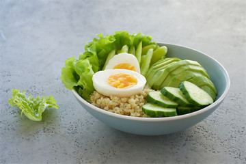 Buddha bowl with quinoa, salad, cucumber, green bell, avocado and eggs The concept of healthy diet. Gray marble background