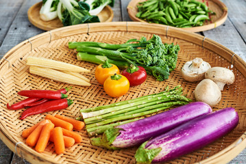 Wicker plate with colorful vegetables on an old table. Healthy eating concept.