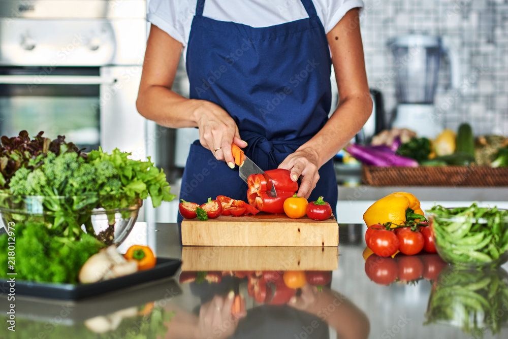 Wall mural housewife cutting vegetables on salad in kitchen.