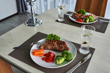 Grilled beefsteak and vegetables on the dining table.