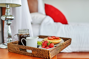 Breakfast in bed with fruits and pastries on a tray.