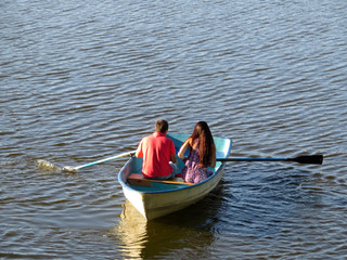 Fototapeta na wymiar Couple in love sailing on a rowing boat. Young man and woman in a boat, romantic date