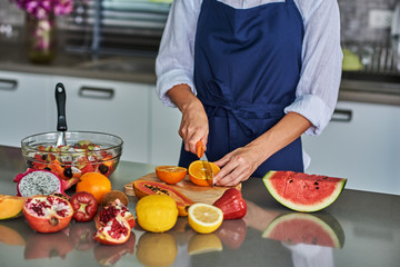 Preparing fruit salad.Cutting orange.