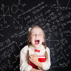 Kids mathematics education concept. Little girl math student on school blackboard background with hand drawings science formula pattern