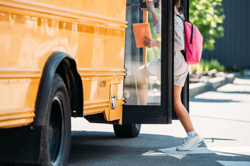 cropped shot of schoolgirl entering school bus