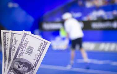 Money dollars on the background of a TV on which the game is shown tennis, sports betting, dollars