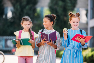 Fototapeta premium happy schoolgirls with notebooks spending time together after school