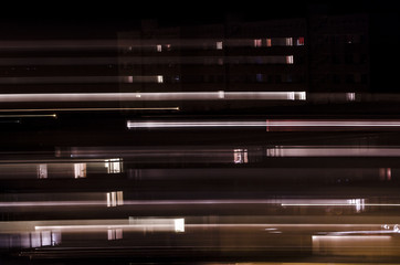 Abstract, blurry night shot of lights in windows in block building. Concept of time travelling   
