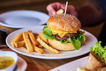 Fresh tasty burger and french fries on wooden table.