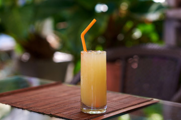 Glass of freshly squeezed orange juice with straw  on wooden table.