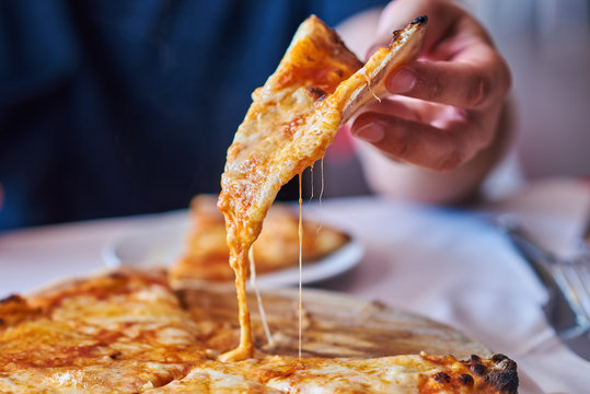 Close up a hot pizza slice with dripping mozzarella cheese.