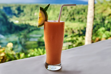 Smoothie with tropical fruits: mango, banana, pineapple in a glass  on on the table.