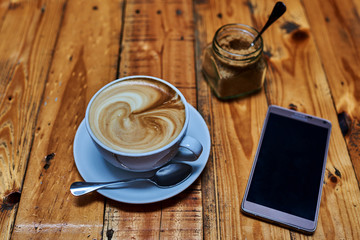 Coffee latte and smartphone on wooden table.