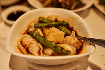 Closeup on plate of steamed dumplings with soy sauce.