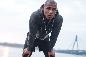 Young male jogger athlete training and doing workout outdoors in