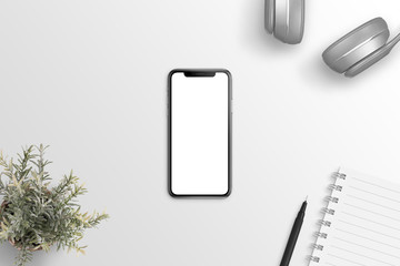 Thin smart phone with tooth on screen. Blank screen for mockup. Flat lay scene with headphones, plant, notepad and pen.