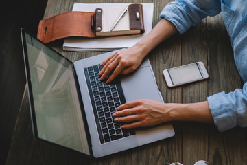 Cropped shot view of a woman's hands keyboarding on laptop, young female person working on netbook while sitting in office, female freelancer connecting to internet via computer. Selective focus.