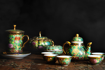 Still life of porcelain tea or coffee set of pot, jar cups and mug on wooden table with scrattered...