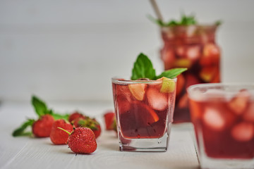 Cold sangria in a glass on white background. Summer cold drinks: homemade  sangria with ice cubes, and mint in glass on wooden background. Sangria with slices of fruit and ice, selective focus.