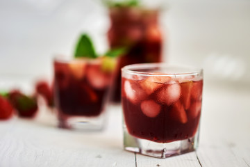 Refreshing sangria or punch with fruits in glasses and pitcher.  Traditional summer drink beverage. Red wine, strawberries, oranges, lemon, and green apple. On a wooden rustic table with copy space..