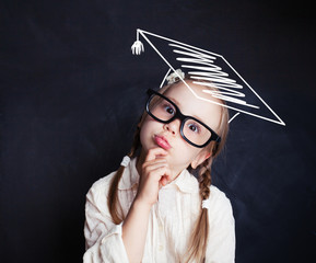 Smart kid thinking. Little girl in graduation hat