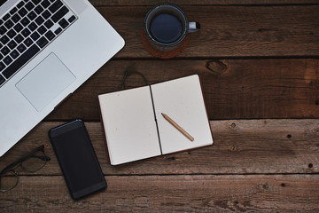 Business concept with copy space. Office desk table. Working space with blank notepad, laptop, glasses smartphone and mug coffee on the vintage wooden table. Vintage style.