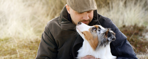 Mensch und Hund, outdoor in herbstlicher Landschaft schauen sich voller Vertrauen und Liebe in die Augen. - 218022315