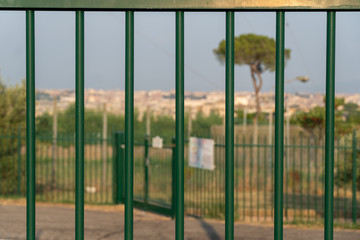 Out of focus cityscape in the distance viewed through an iron fence. Selective focus