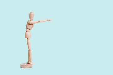 The wooden mannequin points away with his hand. Pointing something, showing someone. The wooden figure stretches out his hand.