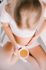overhead view of pregnant woman with cup of tea at home
