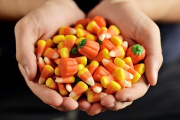 Candy corn and pumpkin in male hands. Halloween party.