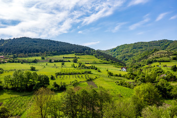 Fototapeta na wymiar Serbian rural village green springtime landscape, mountains in Serbia are very beautiful, near Valjevo. Valley and hills. White house, farmland and spring forest in spring. European countryside