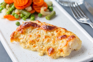 Baked cod fish fillet under cheese, mustard, pepper and cream crust, served with steamed vegetables, horizontal