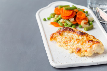 Baked cod fish fillet under cheese, mustard, pepper and cream crust, served with steamed vegetables, horizontal, copy space