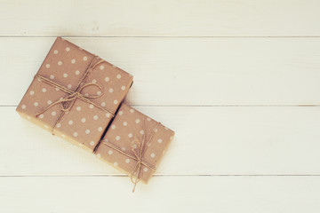 Boxes in craft paper, eco paper on the wooden table. Parcels or gifts tied with twine. Brown paper wrapped gift box with rope bow on a old rustic wood background. Background for your design.