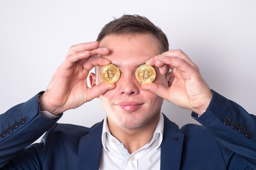 A man holds a coin bitcoin in front of his eyes. In the eyes of money (bitcoin)