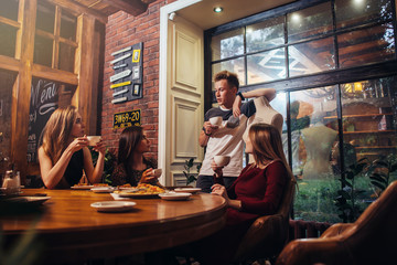 Serious young people sitting in a fashionable cafe drinking tea discussing