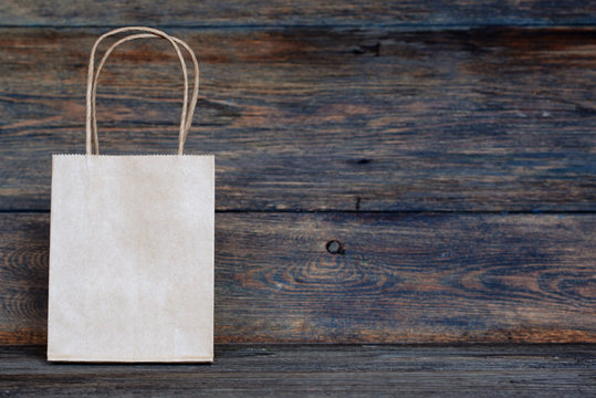 Sale, consumerism and advertisement concept -  blank  brown paper  bags on the vintage wooden board background. Paper bags with handles, blank craft shopping bag with area for your logo or design.
