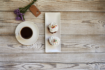 A cup of coffee and colorful almond cookies macaroon on white rustic wooden table. Breakfast on Mothers day, Valentines Day or Womens day. Spring morning concept. Top view. Copy space.
