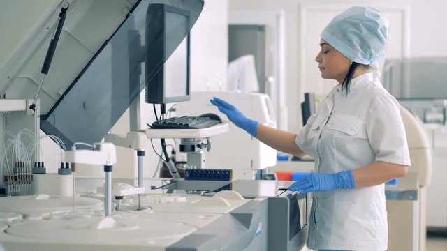 Female lab expert is managing Automatic Pharmaceutical Equipment.